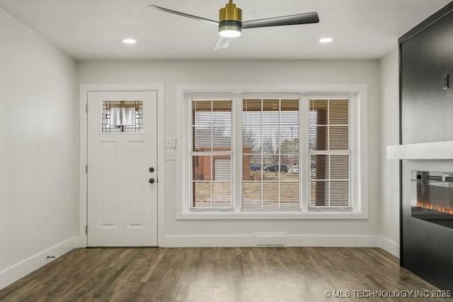 doorway with a ceiling fan, baseboards, wood finished floors, and a glass covered fireplace