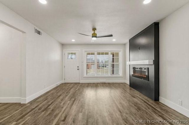 unfurnished living room featuring a large fireplace, wood finished floors, visible vents, and baseboards