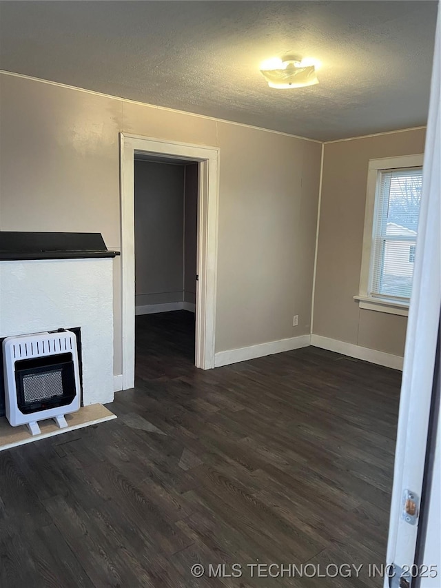 unfurnished living room featuring heating unit, a textured ceiling, baseboards, and dark wood-style flooring