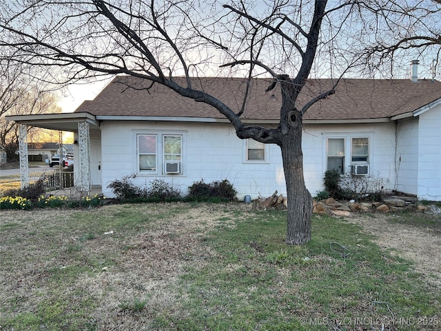 exterior space featuring a carport, a lawn, and roof with shingles