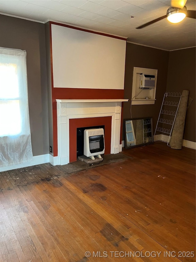 unfurnished living room with a wall unit AC, crown molding, heating unit, wood-type flooring, and a ceiling fan