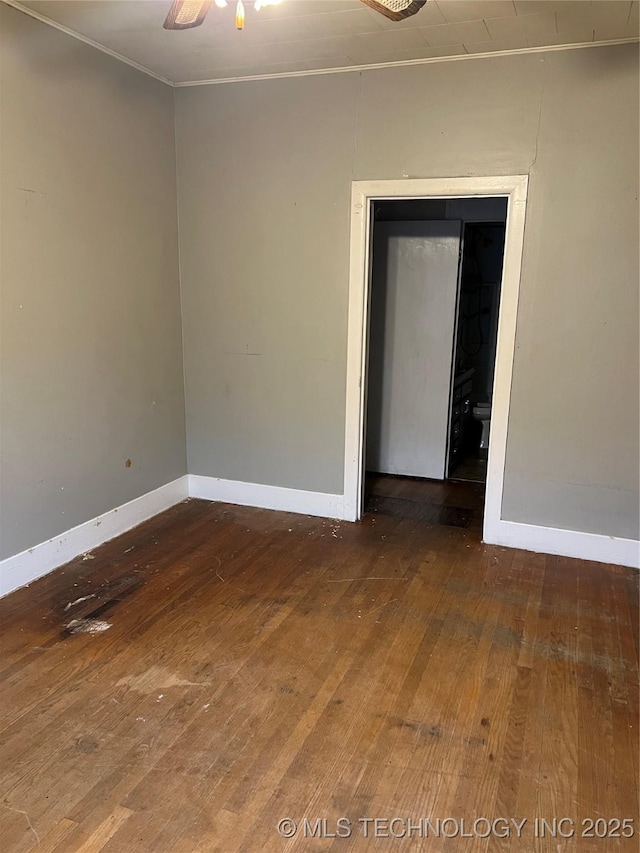 empty room with baseboards, hardwood / wood-style floors, a ceiling fan, and crown molding