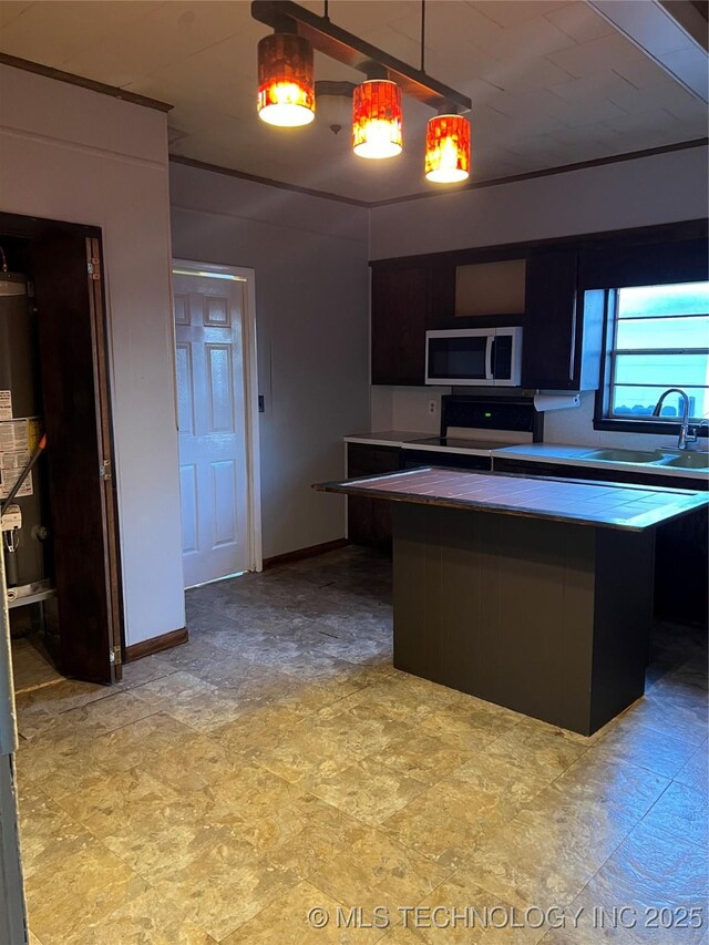 kitchen featuring baseboards, electric stove, stainless steel microwave, pendant lighting, and a sink