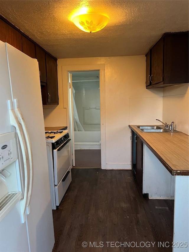 kitchen featuring a textured ceiling, white appliances, dark wood-type flooring, and a sink