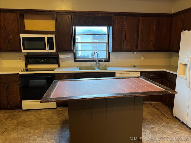 kitchen with white refrigerator with ice dispenser, range with electric cooktop, tile countertops, stainless steel microwave, and a sink