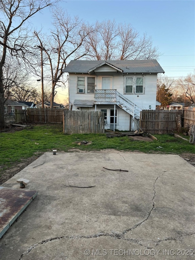 rear view of property featuring stairs, fence, and a lawn