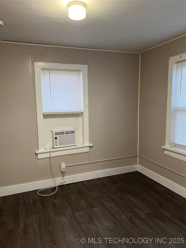 spare room with a textured ceiling, dark wood-style flooring, cooling unit, and baseboards