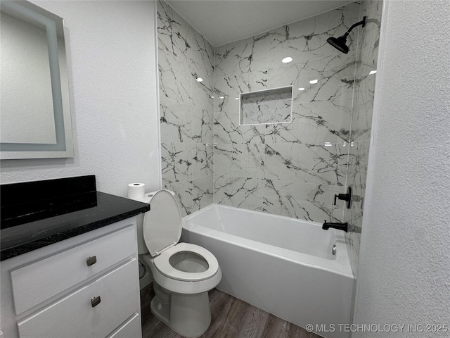 full bath featuring a textured wall, toilet, wood finished floors, vanity, and  shower combination