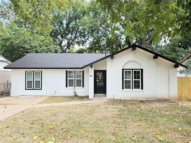 ranch-style home with a shingled roof, fence, a front lawn, and brick siding