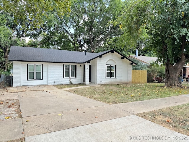 ranch-style house with brick siding, fence, a front lawn, and roof with shingles