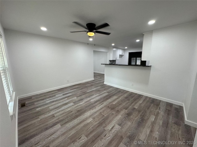 unfurnished living room featuring dark wood-type flooring, recessed lighting, ceiling fan, and baseboards