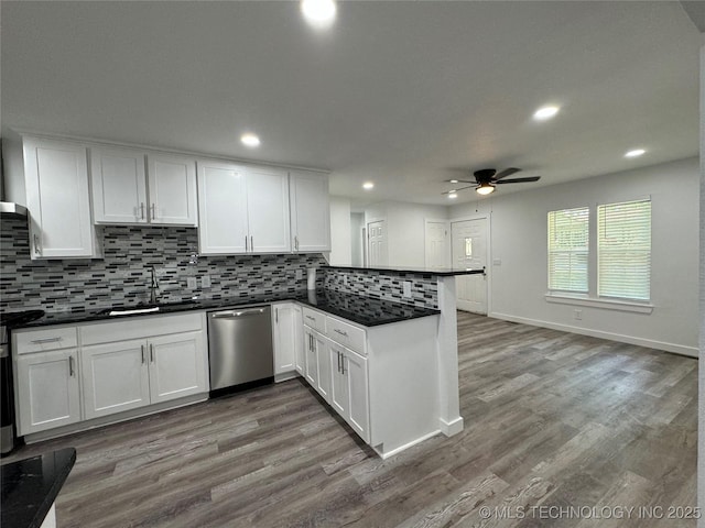 kitchen featuring a peninsula, wood finished floors, white cabinetry, dishwasher, and dark countertops