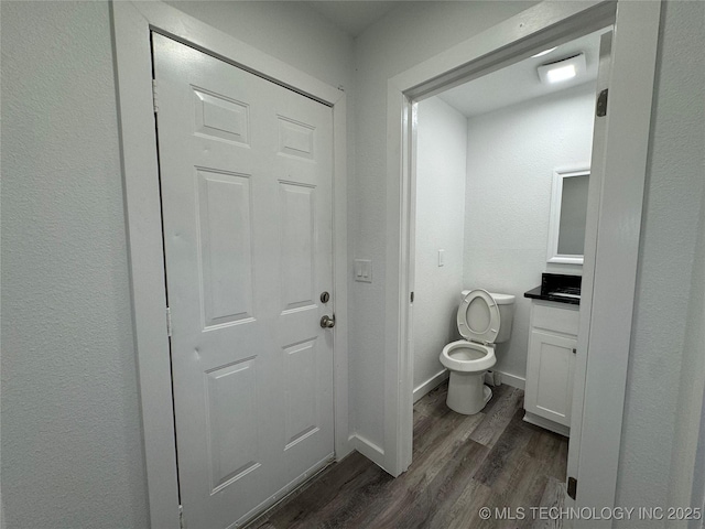 bathroom with toilet, baseboards, wood finished floors, and vanity