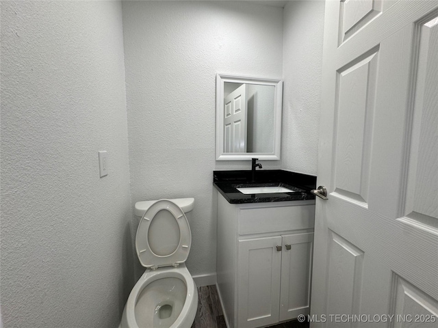 bathroom featuring a textured wall, vanity, and toilet