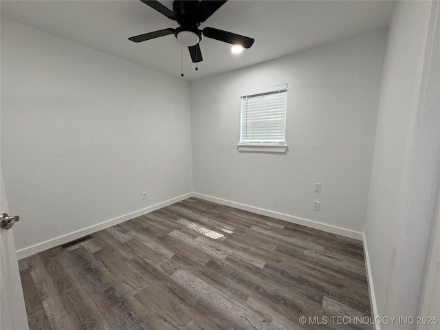 empty room featuring a ceiling fan, visible vents, dark wood finished floors, and baseboards