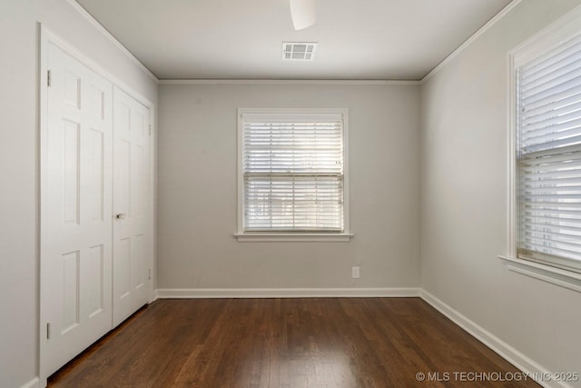 unfurnished bedroom featuring visible vents, baseboards, dark wood-type flooring, and a closet