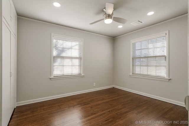 unfurnished room featuring visible vents, plenty of natural light, crown molding, and dark wood-type flooring