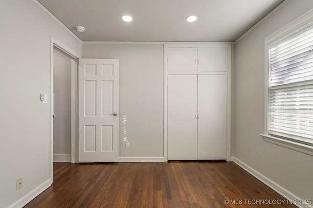 unfurnished bedroom with a closet, dark wood-type flooring, and baseboards