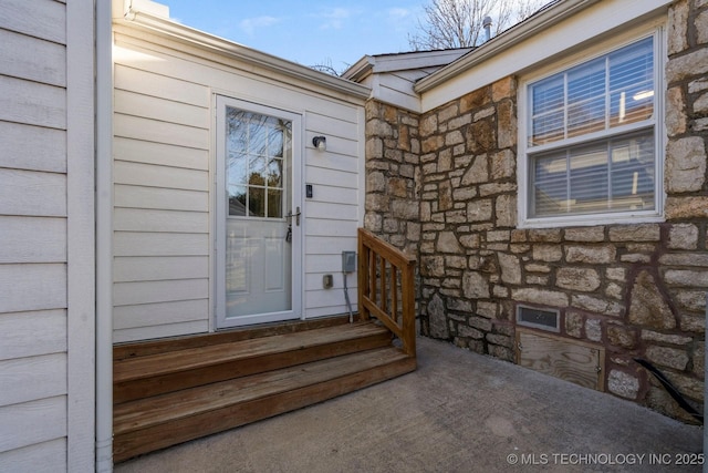 entrance to property featuring visible vents and stone siding