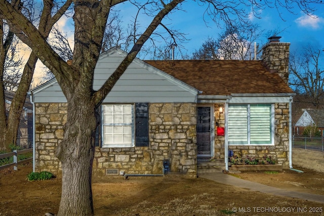 view of front of house featuring stone siding, a chimney, and fence