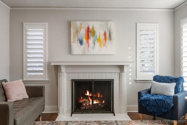 living area featuring a fireplace, crown molding, and wood finished floors