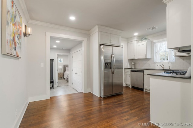 kitchen featuring visible vents, a sink, tasteful backsplash, dark countertops, and appliances with stainless steel finishes