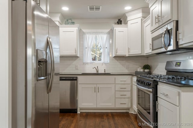 kitchen featuring visible vents, dark wood-type flooring, a sink, dark countertops, and appliances with stainless steel finishes