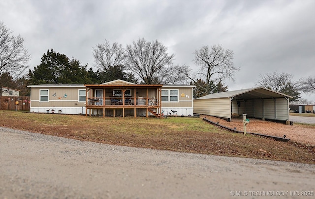 manufactured / mobile home with a carport, a wooden deck, and a front lawn