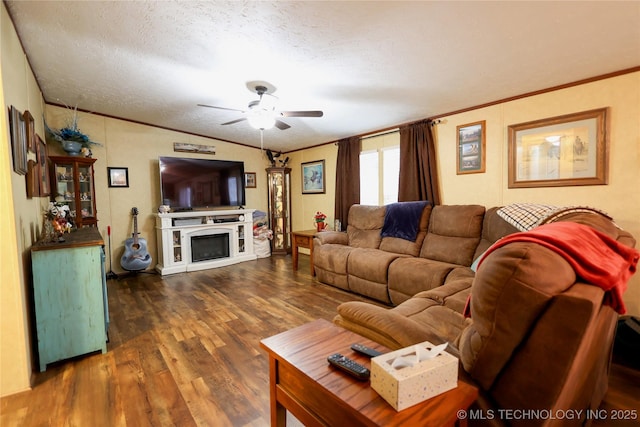 living room featuring lofted ceiling, a fireplace, wood finished floors, a ceiling fan, and crown molding