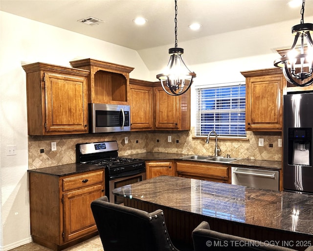 kitchen with decorative backsplash, lofted ceiling, appliances with stainless steel finishes, a sink, and a notable chandelier