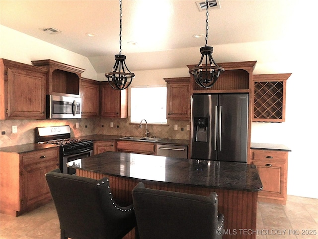 kitchen featuring stainless steel appliances, a sink, visible vents, tasteful backsplash, and decorative light fixtures