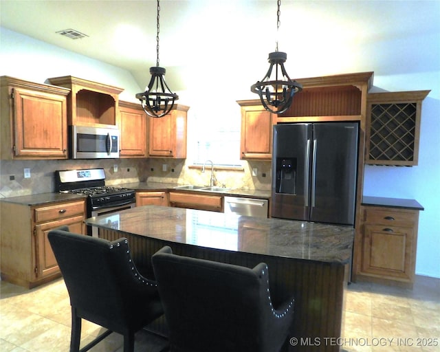 kitchen featuring stainless steel appliances, a sink, visible vents, tasteful backsplash, and pendant lighting