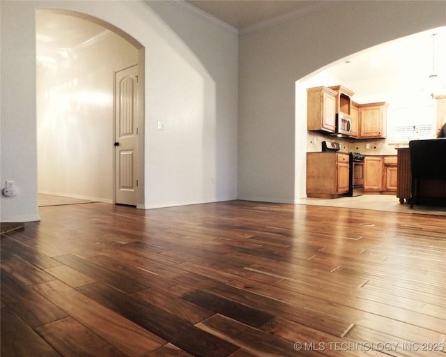 unfurnished living room featuring baseboards, crown molding, arched walkways, and wood finished floors