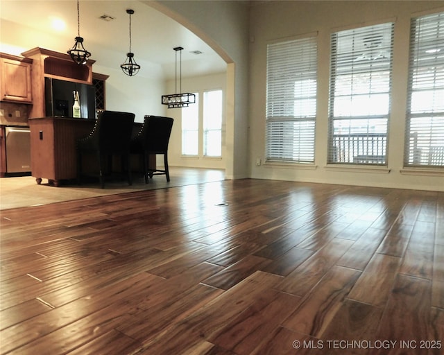 living area featuring arched walkways, visible vents, and wood finished floors