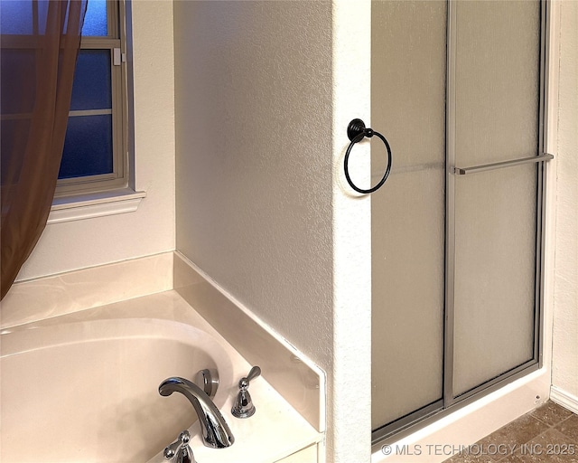 full bathroom featuring a textured wall, a shower with door, and a bath