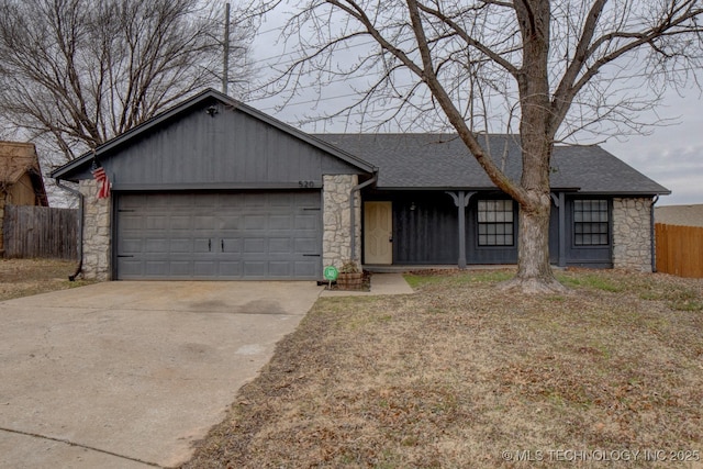 view of front of property featuring a garage, stone siding, fence, and roof with shingles