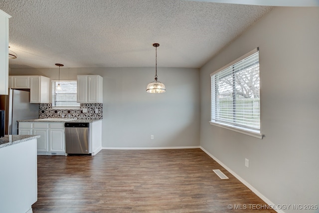 kitchen with tasteful backsplash, white cabinets, dark wood-type flooring, stainless steel appliances, and pendant lighting