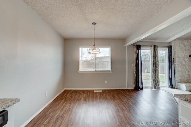 unfurnished dining area with visible vents, a textured ceiling, baseboards, and wood finished floors