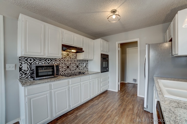 kitchen featuring decorative backsplash, white cabinets, a sink, under cabinet range hood, and black appliances