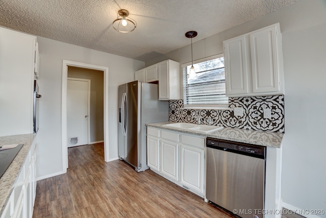 kitchen with stainless steel appliances, light countertops, light wood-style flooring, white cabinets, and a sink