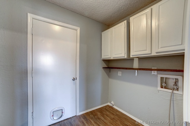 washroom featuring a textured ceiling, washer hookup, baseboards, cabinet space, and dark wood-style floors