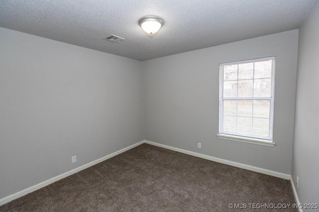 unfurnished room with a textured ceiling, dark carpet, visible vents, and baseboards