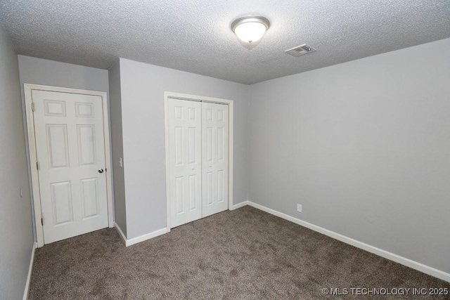 unfurnished bedroom featuring a textured ceiling, visible vents, baseboards, a closet, and carpet