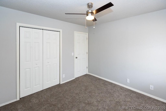 unfurnished bedroom with a closet, dark carpet, a textured ceiling, and baseboards