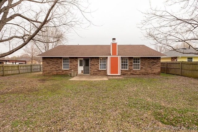 back of property featuring brick siding, a chimney, a patio area, and a fenced backyard