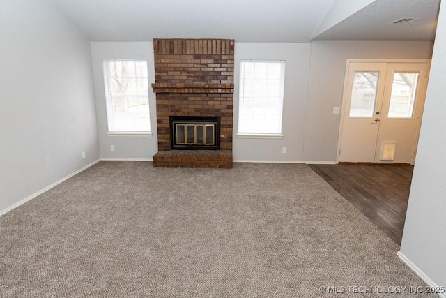 unfurnished living room featuring baseboards, visible vents, plenty of natural light, and a fireplace