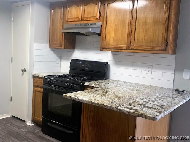 kitchen with black gas stove, under cabinet range hood, brown cabinetry, and decorative backsplash