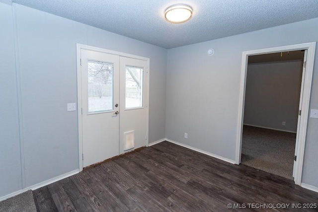 spare room with dark wood-type flooring, french doors, a textured ceiling, and baseboards