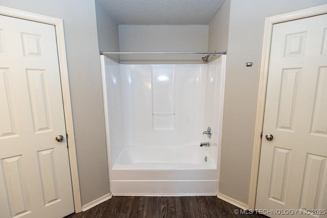 full bathroom with baseboards, a textured ceiling, shower / tub combination, and wood finished floors