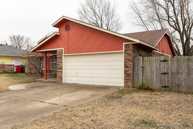 view of front of property featuring a garage, concrete driveway, brick siding, and fence